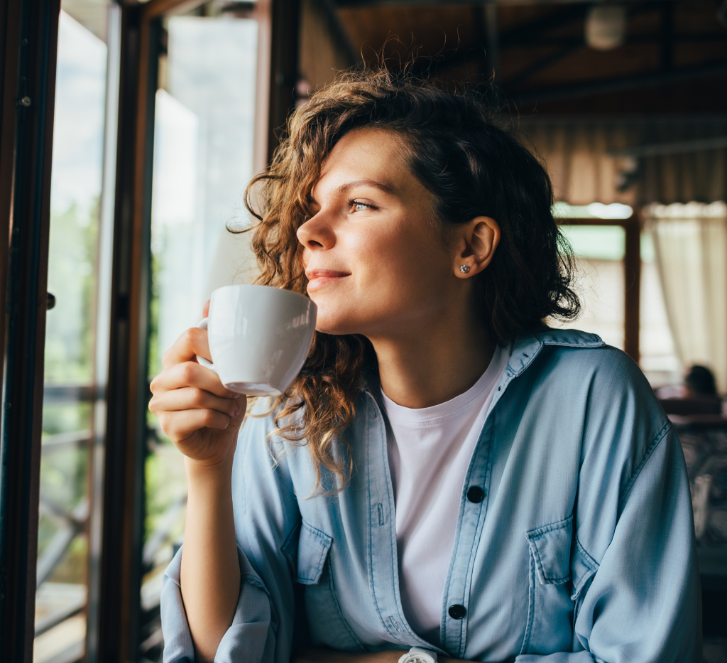 Girl drinking coffee and looking out the window